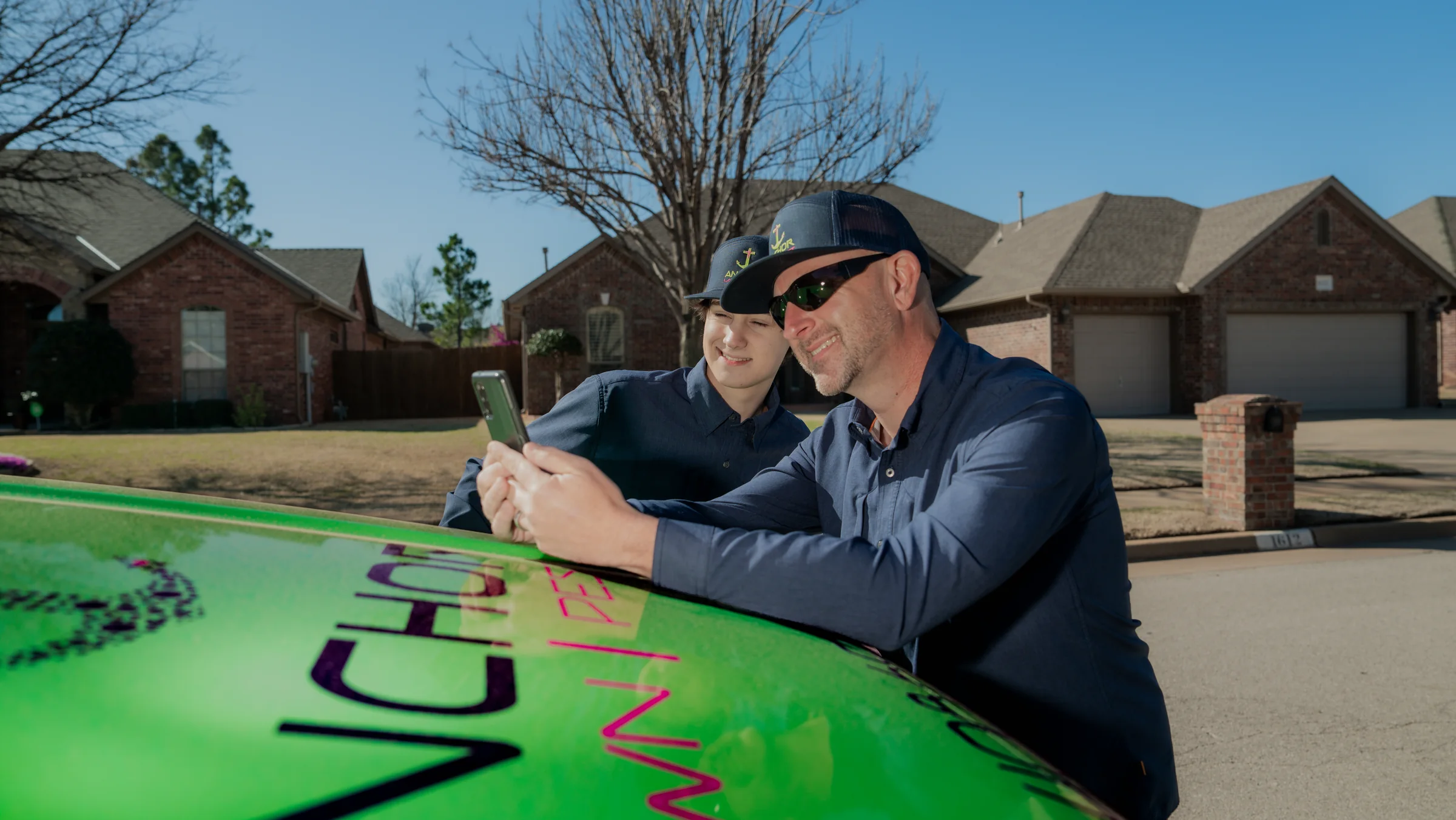 Two lawn and pest operators reviewing property information beside a service vehicle