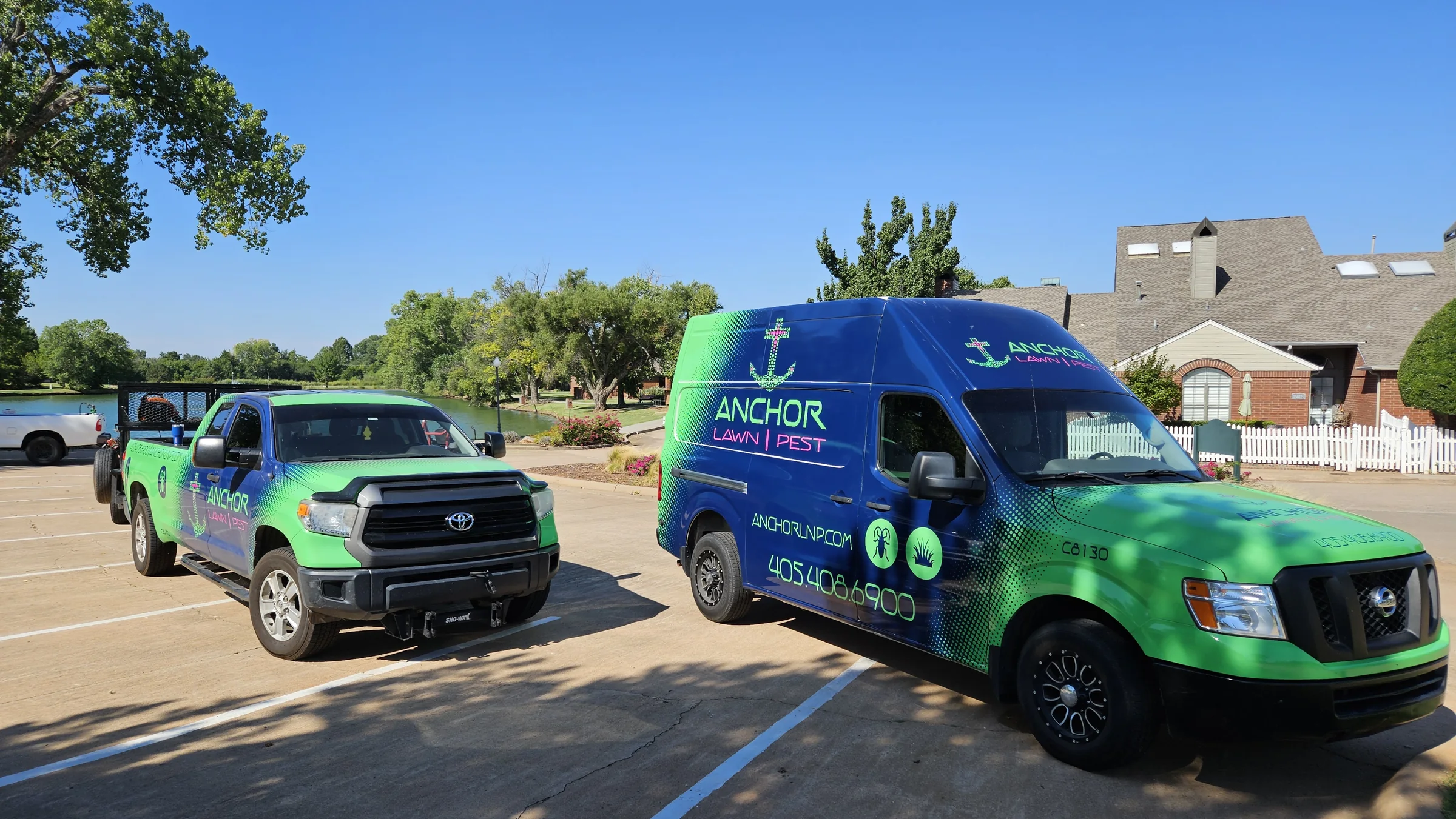Branded lawn and pest truck and service van parked near a residential property