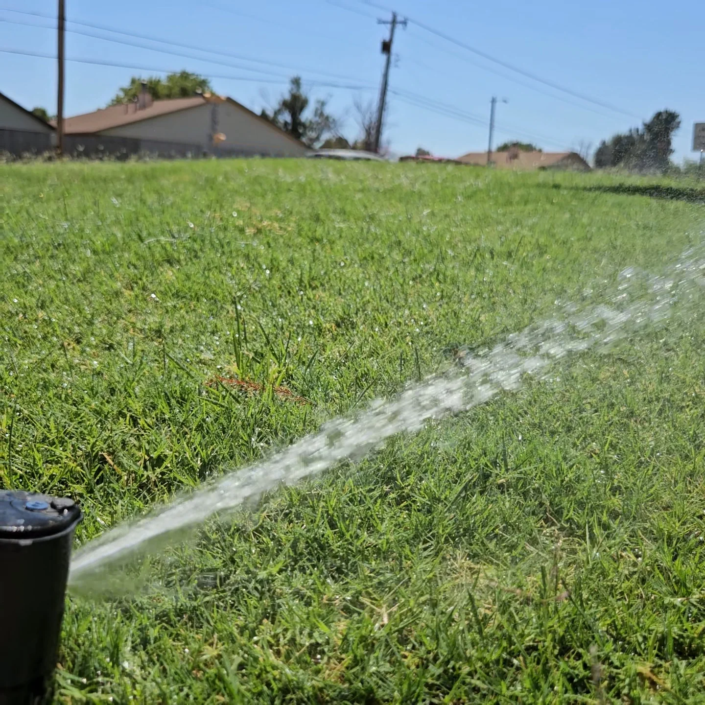 Sprinkler head running during an irrigation zone test on a lawn