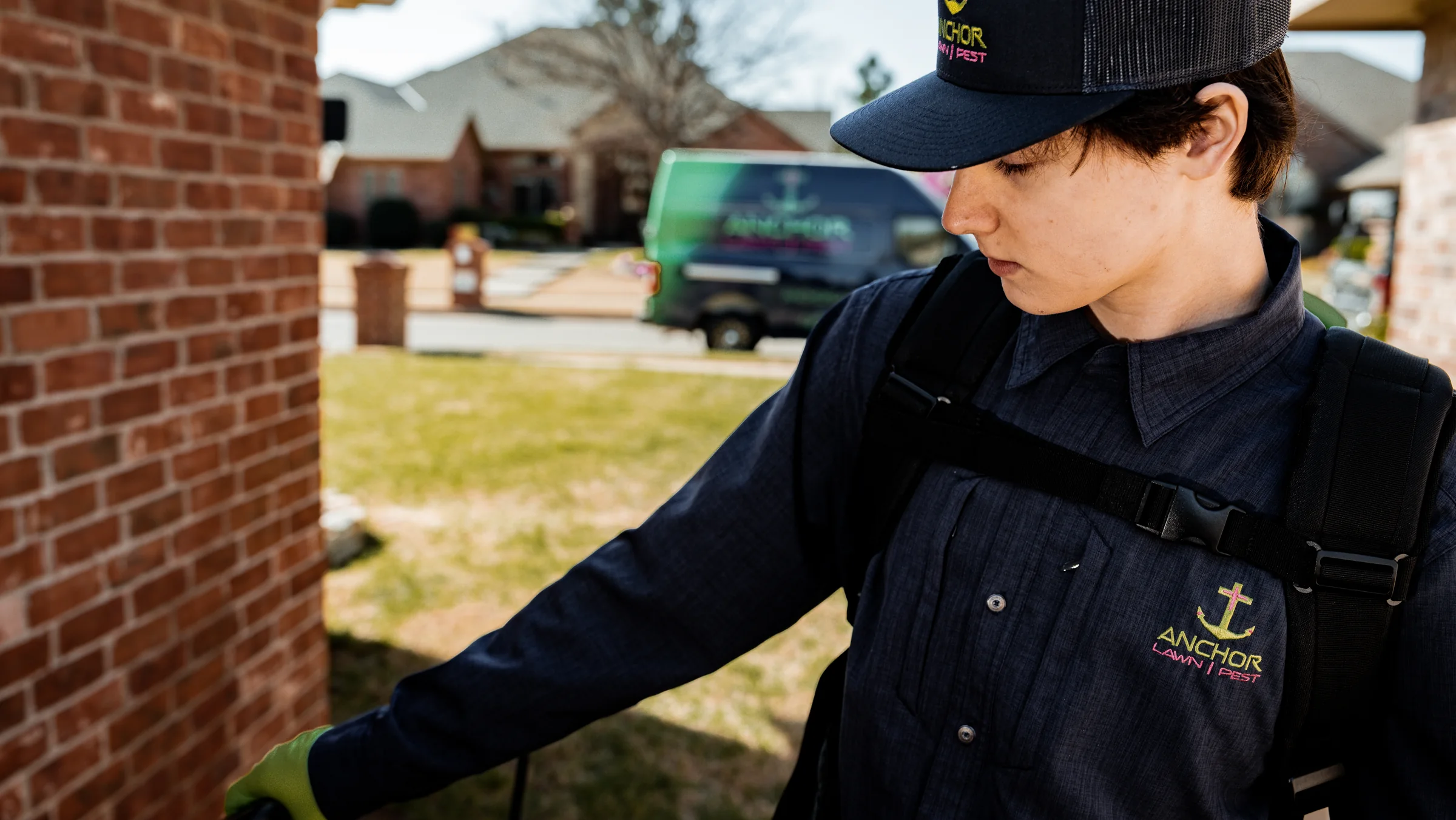 Pest technician inspecting and treating an exterior wall